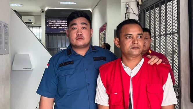 
					<em>Arisandi, Kepala Desa Tanjung Garbus II, saat ditahan oleh Kejari Deli Serdang atas dugaan korupsi dana desa, Kamis (13/3/2025).</em>