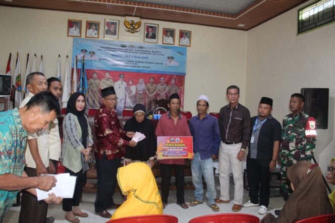 
					Kepala Desa Tanjung Baru dan Babinsa saat menyerahkan langsung BLT Dana Desa kepada salah satu KPM di Balai Desa Tanjung Baru.