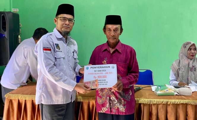 
					Kepala Desa Sungai Baung, Ridwan, menyerahkan BLT Dana Desa secara simbolis kepada salah seorang penerima di Aula Kantor Desa Sungai Baung.