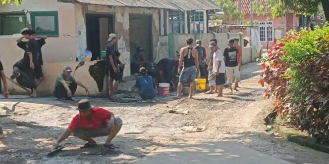
					Warga Desa Japura Kidul bersama aparat desa bergotong royong menambal jalan poros desa yang berlubang, Senin (2/6/2025).