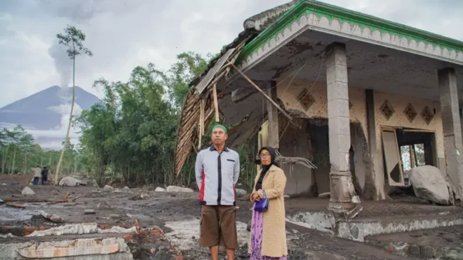 
					Dua warga sedang berdiri dengan latar rumah yang setengah hancur akibat dampak erupsi Semeru. (ANTARA FOTO/Irfan Sumanjaya)