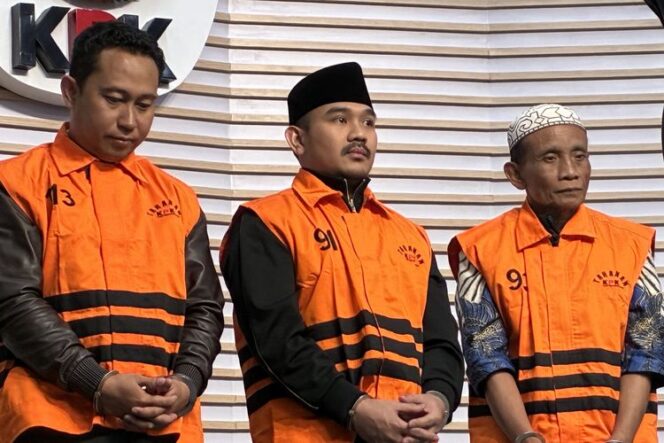 
					Komisi Pemberantasan Korupsi (KPK) menetapkan Bupati Bekasi Ade Kuswara Kunang (tengah), HM Kunang (tiga dari kiri) selaku ayah Bupati, dan Sarjan (kiri) selaku pihak swasta, sebagai tersangka terkait kasus dugaan suap ijon proyek di Kabupaten Bekasi pada Sabtu (20/12/2025).(Image courtesy: KOMPAS.com)