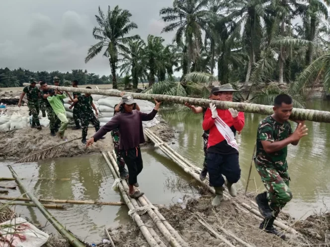 
					TNI bersama warga Desa Stabat Lama, Kecamatan Wampu, Kabupaten Langkat, melaksanakan perbaikan tanggul yang kembali jebol akibat hujan deras, Minggu (14/12/2025). (Puspen TNI)