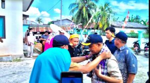 Plt Camat Pasimarannu mengalungkan sarung adat kepada Bupati Kepulauan Selayar dalam Tradisi Penyambutan Kuntau Bonerate.