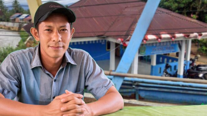 
					Pj Kepala Desa Pyang Mbik, Antoni Novrianto, S.Sos.,dengan latar belakang Balai Desa Pyang Mbik
