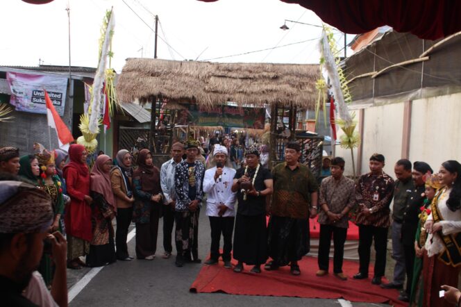 
					Pembukaan Watugede Culture Festival 2026 berlangsung dalam suasana kental dengan nuansa budaya Jawa. Tokoh budaya, unsur masyarakat, panitia, serta peserta mengenakan busana tradisional dalam prosesi pembukaan di jalan desa. Latar gerbang bernuansa tradisional dan panggung festival mempertegas upaya masyarakat Watugede menghadirkan budaya sebagai bagian dari ruang publik desa.